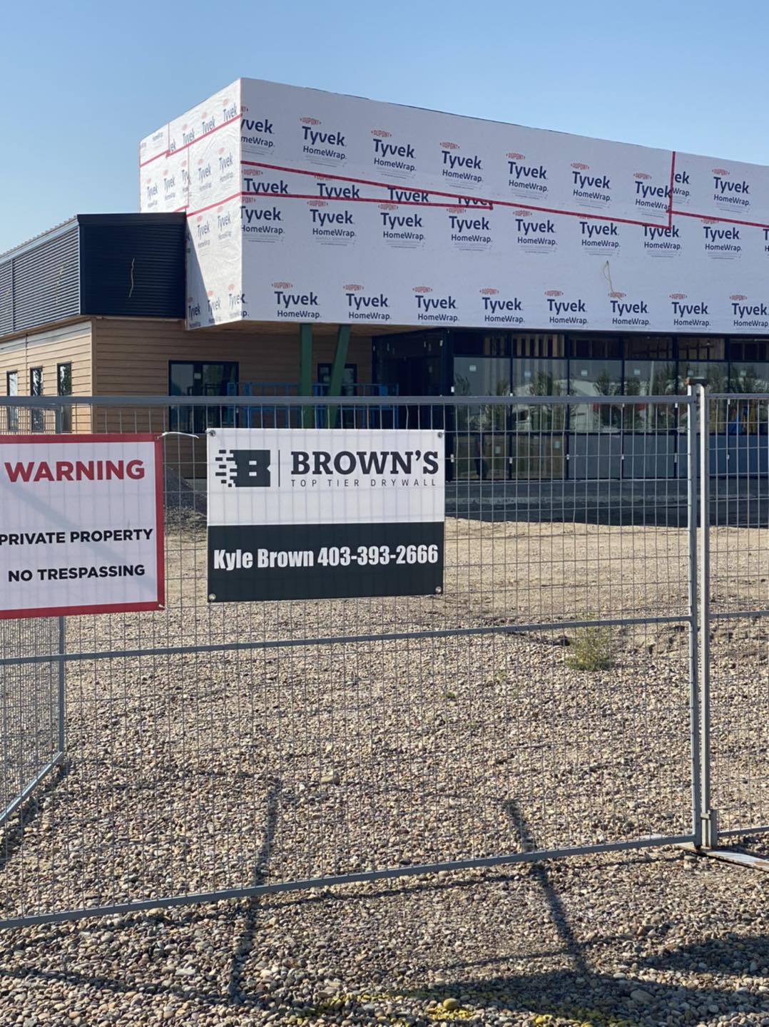 Commercial building with brown's drywall sign on fence